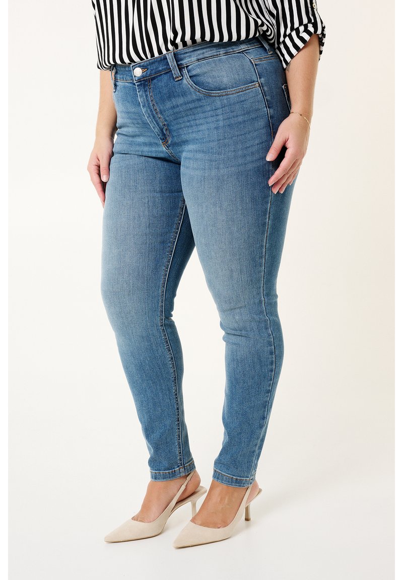 Lichtblauwe skinny jeans van denim, met een middelhoge taille en een klassieke vijf-pocket stijl. Gepaarde met een zwart-wit gestreepte top.