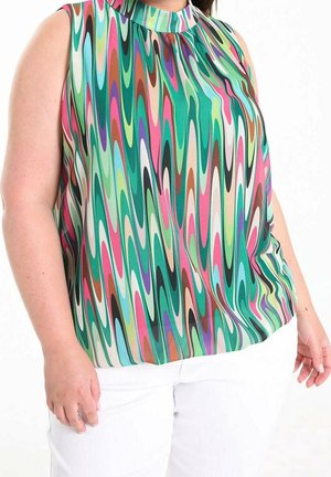 Bezrękawnik z wysokim kołnierzem ozdobiony pionowymi falistymi paskami w kolorze zielonym, różowym, turkusowym, brązowym i białym, noszony z białymi spodniami.