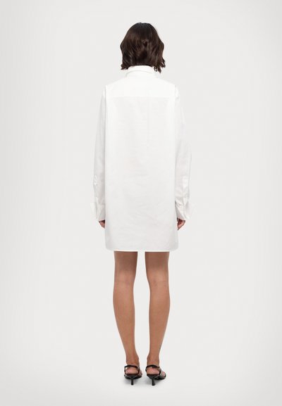 Vit skjortklänning med krage, långa ärmar och knäppte manschetter; mjukt bomullsmaterial; knä-längd; minimalistisk design.