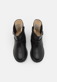 Botas de tobillo de cuero negro con una textura suave, punta redondeada, cremalleras laterales y correas sutiles para añadir detalle.