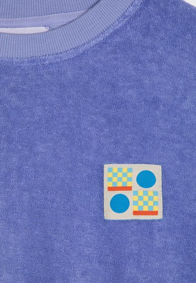 Felpa in felpa di cotone azzurra con scollatura a costine. Caratteristico motivo a patch con una scacchiera e cerchi solidi in blu, giallo e rosso.