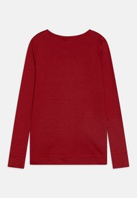 Rød langermet skjorte laget av ribbet stoff, med rund hals og rett kant med sømdetaljer på mansjettene og bunnen.