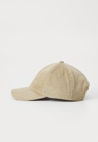 Beige kordfløyels-baseballcaps med strukturert krone, buet skygge og sydd detaljer på sidene.