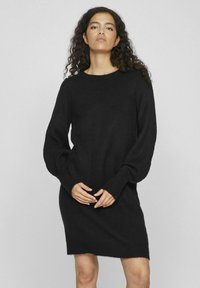 Abito in maglia nera con maniche lunghe e voluminose e colletto girocollo. Texture morbida con una vestibilità dritta e polsini a costine.