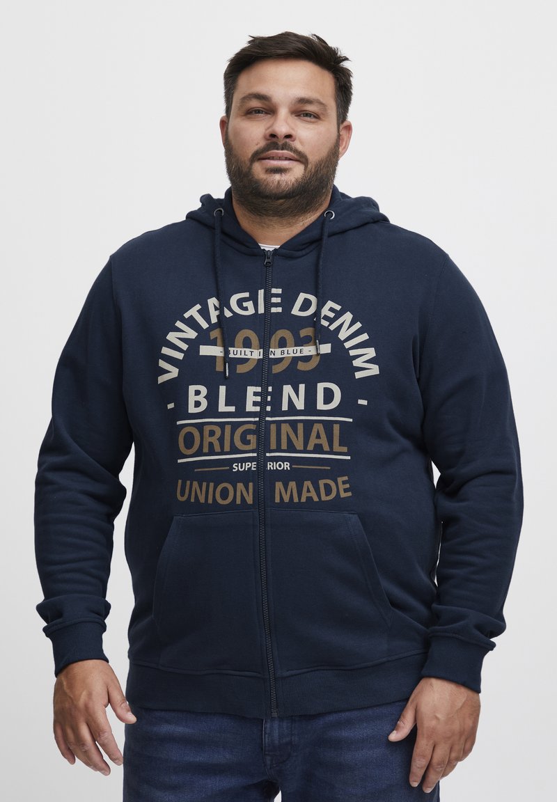 Hoodie zip-up navy realizzato in un tessuto misto cotone; presenta tasche frontali e una stampa grafica con "Vintage Denim" e "Original" in beige.