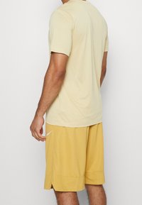 Camiseta atlética de color amarillo claro combinada con pantalones cortos amarillos. La tela es suave, con mangas cortas y un ajuste cómodo. Los pantalones cortos tienen una abertura lateral.