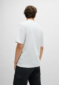 White short-sleeve t-shirt with a crew neck, made of soft fabric; worn with black cargo pants featuring side pockets.