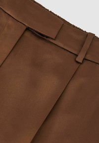 Barna szövet, sima, selymes felülettel, plissé kialakítással és öv részlettel a deréknál.