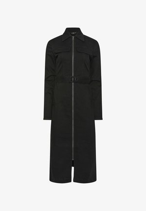 Lange zwarte jurk met rits en kraag, lange mouwen, borstzakken en een riem met een ronde gesp in de taille.