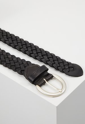 Ceinture en cuir noir tressé avec une boucle métallique argentée arrondie, présentée à plat sur une surface blanche.