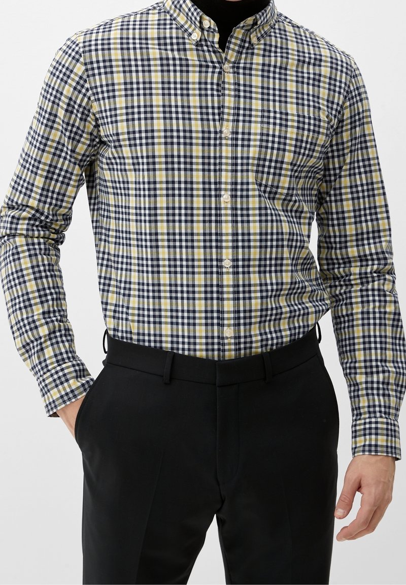 Camicia con bottoni in fantasia a quadri blu navy, gialla e bianca. Tessuto in cotone, maniche lunghe e tasca sul lato sinistro. Design aderente.