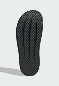 Black shoe sole featuring grooved texture and ridged patterns. Notable logo detail at the heel. Durable rubber material for grip.