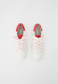 Baskets blanches avec des accents rouges. Semelle en caoutchouc texturée, bout rond et lacets épais et torsadés rouges et blancs. Logo visible sur les semelles intérieures.