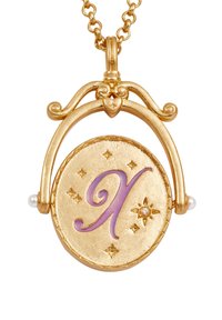 Gouden hanger ketting met een ronde locket met een paarse "X," steraccenten en twee kleine parels, hangend aan een delicate ketting.