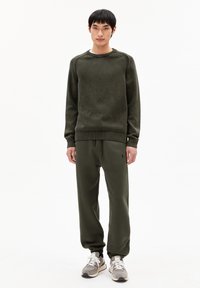 Olivengroen sweater met een geribbelde ronde hals en bijpassende joggers. De sweater heeft een textuurstof; de joggers hebben een tailleband met koord.