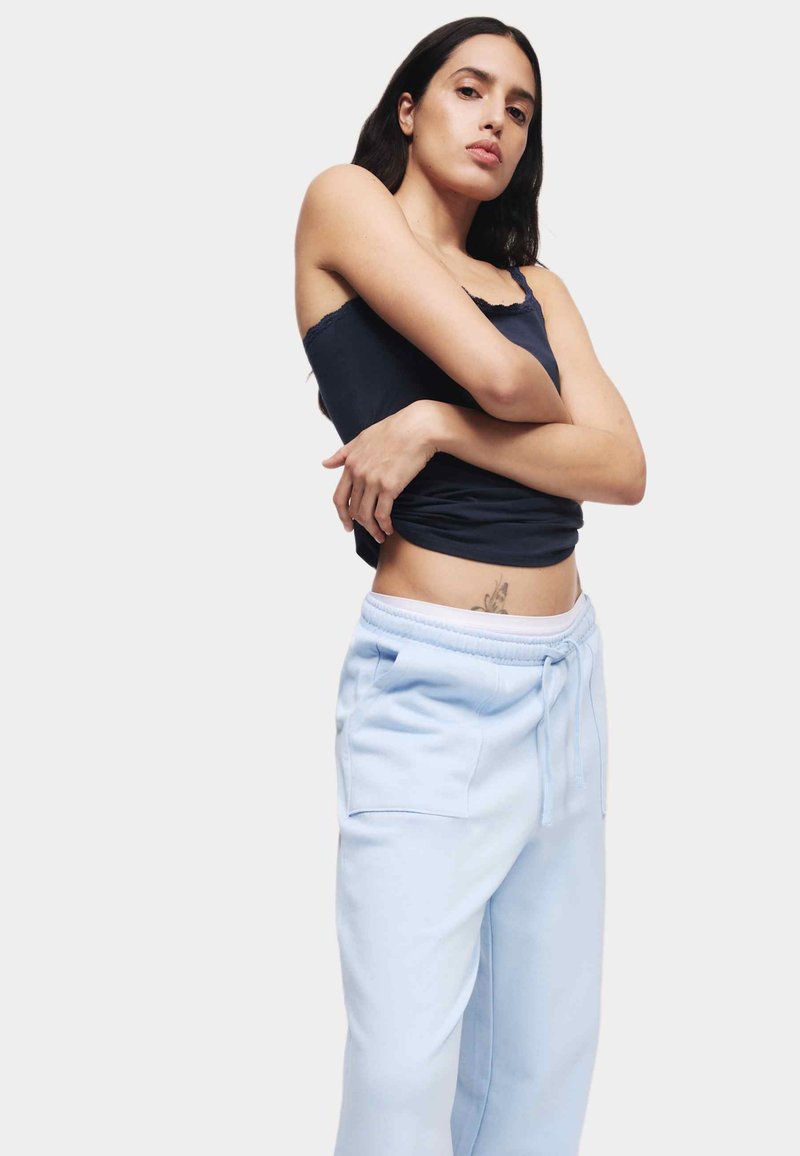Marineblauw tanktop met gekartelde randen, gecombineerd met lichtblauwe joggingsbroek met een elastische tailleband en zijzakken.