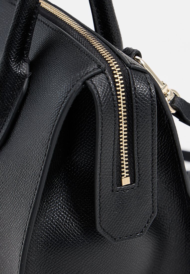 Schwarze strukturierte Handtasche aus strukturiertem Leder, mit goldenen Reißverschluss und glatten Griffen. Kompakte Bauweise mit minimalen Metallakzenten.