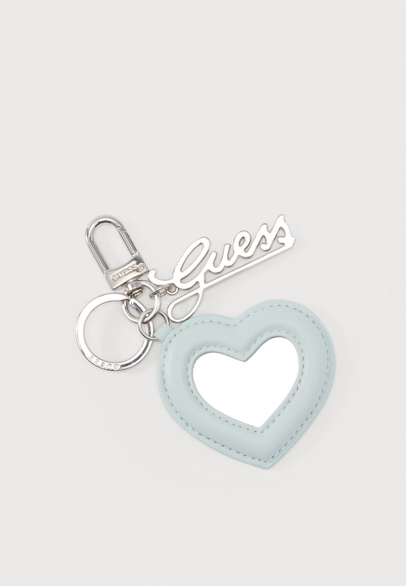 Ασημένιο μπρελόκ με μπλε καρδιά-πλαίσιο που κρατάει έναν καθρέφτη και ένα ασημένιο μενταγιόν με το λογότυπο "Guess", το οποίο είναι προσαρτημένο σε ένα κρίκο και κλείστρο.