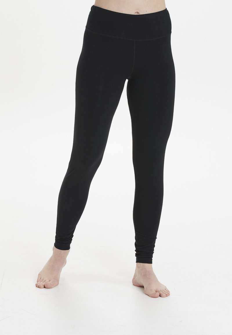 Leggings noirs en tissu extensible avec une taille haute, présentant une texture lisse et une coupe ajustée. Pas de motifs visibles ni de quincaillerie.