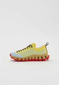Sport shoes featuring a yellow and blue knit upper, brown midsole, and a textured red outsole with circular accents; laced design with a pull tab.