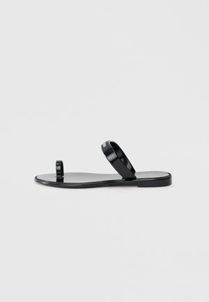 Black flat sandals with a smooth, glossy finish. Features a toe post and two slender straps. Minimalist design with a flat sole.