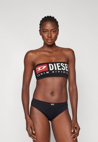 Sort bandeau-top med "DIESEL" logo i hvid og rød, parret med sorte bikini-bunddele med et mærke. Glat, tætsiddende stof.