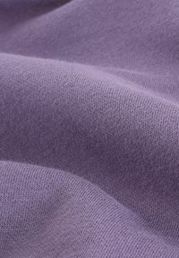 Tissu en tricot lilas doux avec des points fins et uniformes, et de légères plis mettant en valeur la texture et la douceur.