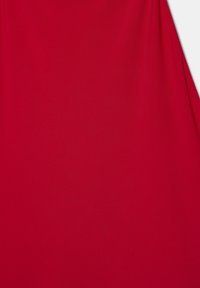 Gros plan d'un tissu rouge lisse avec un léger pli diagonal sur le côté droit et une texture subtile visible.
