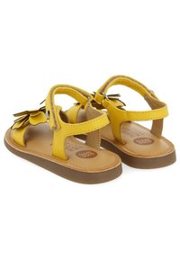 Sandales en cuir jaune avec des accents floraux, bout et talon ouverts, sangle réglable et semelle en caoutchouc marron. Intérieur avec marquage.