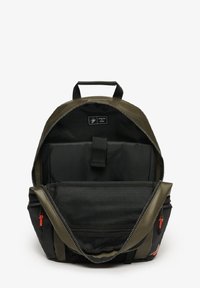 Sac à dos en combinaison de matériaux vert olive et noir, avec un intérieur zippé, une poche en mesh et des accents de fermeture éclair orange.