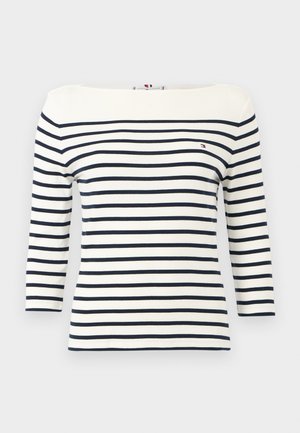 Balta krekls ar garām piedurknēm, horizontālām tumši zilām svītrām un nelielu Tommy Hilfiger logotipu kreisajā krūtīs.