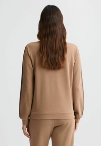 Bruine sweatshirt met lange mouwen, textuurstof, ribgebreide cuffs en zoom, en zijaccenten in een contrasterend materiaal. Eenvoudig, atletisch ontwerp.