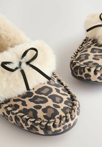 Sandaalit leopardinauhalla, joissa on pehmeä vauvanvaalea tekoturkisvuori ja koristeellinen musta rusetti. Suede-materiaalia, jossa on kontrastivärinen ompelu ja kumipohja.