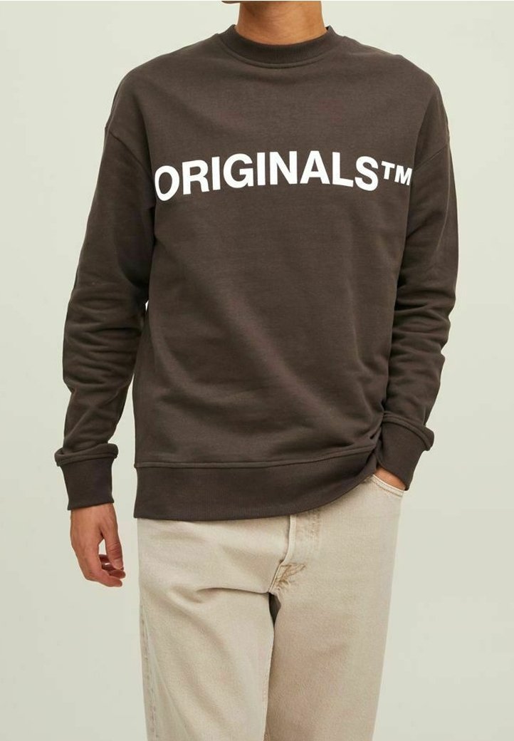 Felpa marrone con il grande testo bianco "ORIGINALS™" che attraversa il petto. Collo a giro, maniche lunghe e polsini a costine. Tessuto morbido.