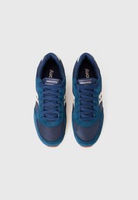 Navy blue sneakers with suede and mesh materials, featuring a white logo and accents. Rounded toe, paired laces, and rubber sole.