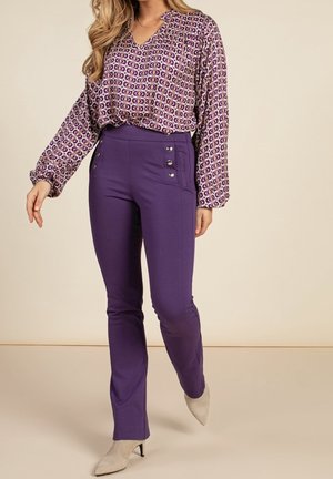Pantalon évasé violet à boutons latéraux associé à un chemisier à manches longues à motifs dans les tons violets et crème. Tissu lisse et doux.