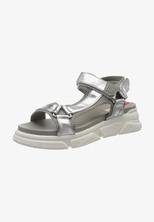 Silver metallic sandals with wide straps, adjustable hook-and-loop closure, textured white platform sole, and pronounced tread pattern.