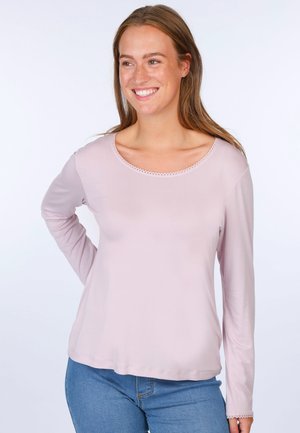 Light pink long-sleeve shirt with a round neckline, featuring delicate lace trim and a relaxed fit, paired with blue jeans.