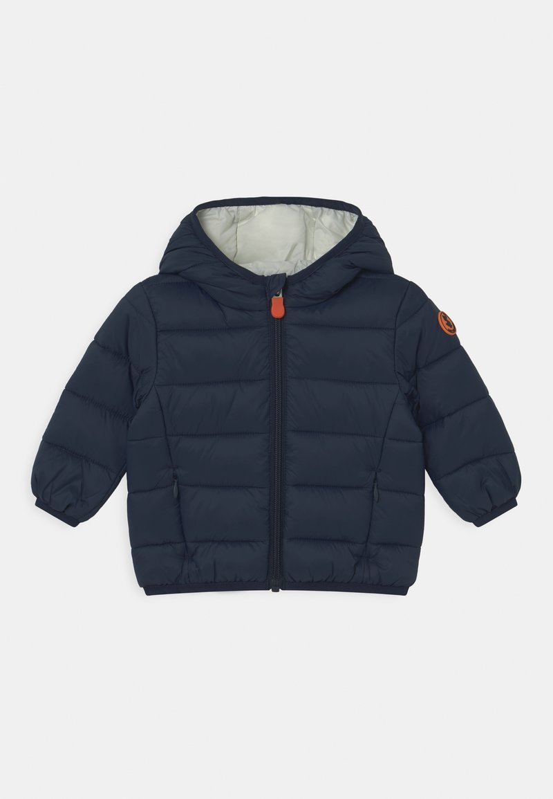 Marineblauwe gewatteerde jas met capuchon, met een ritssluiting aan de voorkant, elastische manchetten en een oranje accent nabij de schouder. Gequiltetextuur.