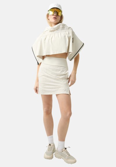 Witte crop top met een relaxte pasvorm, hoge taille rok en chunky sneakers. Reflecterende zonnebril en pet inbegrepen; heeft een gladde textuur en minimale patronen.