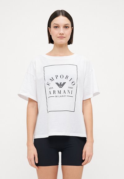 Tricou alb din bumbac, cu un mare grafic logo negru într-un contur rectangular. Mâneci scurte, croială lejeră, asortat cu șorturi negre.