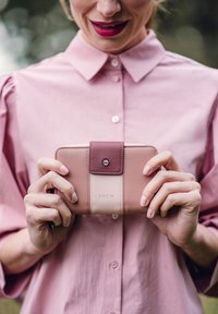 Pink and beige wallet with a textured leather finish, featuring a darker leather accent and a logo. Zipper closure and compact design.