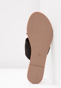 Sandale en daim noir avec une semelle plate en caoutchouc beige. Affichant la taille 37 sur la base, conçue avec un bout ouvert et un style minimaliste.