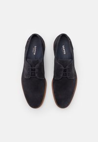 Dunkelblaue Wildlederschuhe mit glatter Oberfläche, runder Spitze und zweilöchrigem Schnürdesign. Beigefarbenes Nähen und ein kontrastierendes Sohlen-Detail.