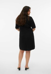 Robe noire arrivant aux genoux en tissu lisse, avec des manches courtes et un décolleté légèrement arrondi, au design décontracté.