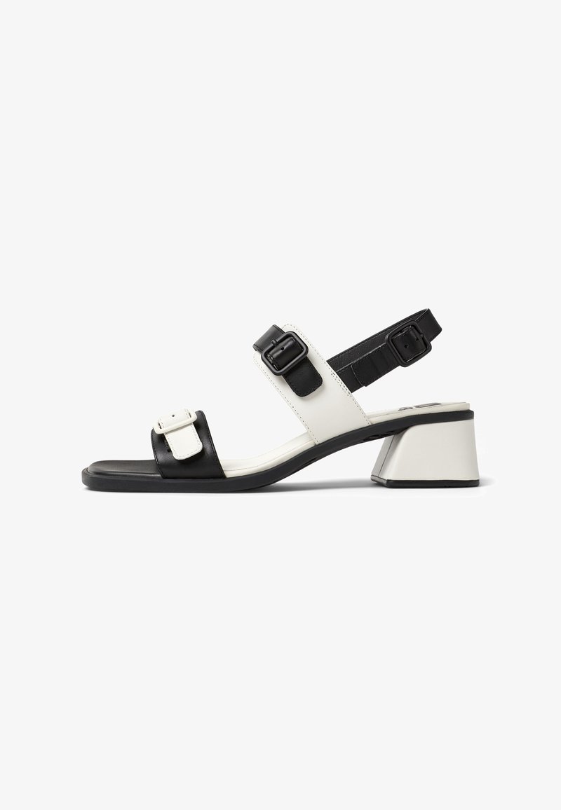 Sandale à talon bloc bas avec brides en cuir noir et blanc et boucles noires réglables, bout ouvert et bride arrière pour le maintien.