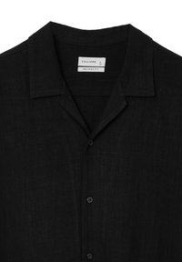 Camicetta nera a maniche corte con vestibilità rilassata, realizzata in tessuto leggero. Presenta colletto a punta e chiusura con bottoni, con una texture sottile.