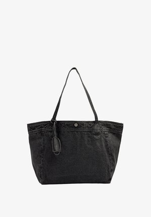 Czarna torba typu tote z denimu z dwoma paskami na ramię, zapięciem na guzik oraz ozdobną zawieszką na białym tle.