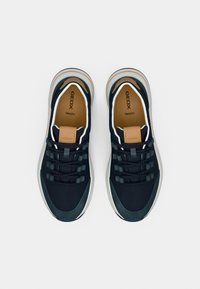 Αθλητικά παπούτσια από δίχτυ σε ναυτικό μπλε με μπεζ λεπτομέρειες, στρογγυλή μύτη, χοντρή λευκή σόλα και γκρι διακοσμητικά στοιχεία. Διαθέτουν ελαστικά κορδόνια και λογότυπο στη γλώσσα.