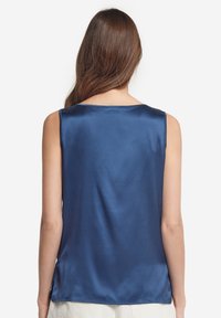 Marineblå satinlinne med en slät yta, ärmlös design och rundad nacke på baksidan. Har sidoklipp vid fållen.